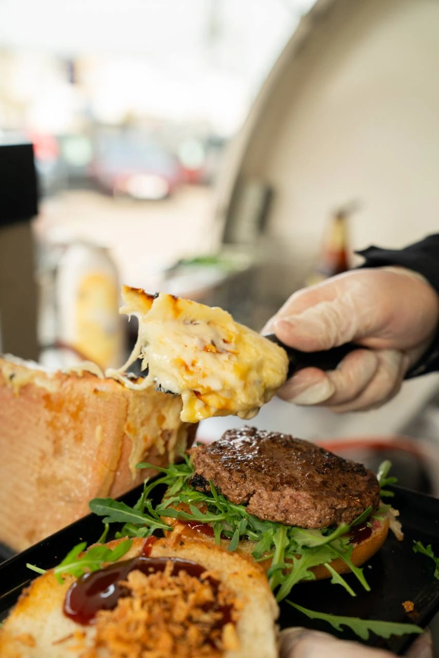 Heißer Raclettekäse wird auf einen Burger gestrichen